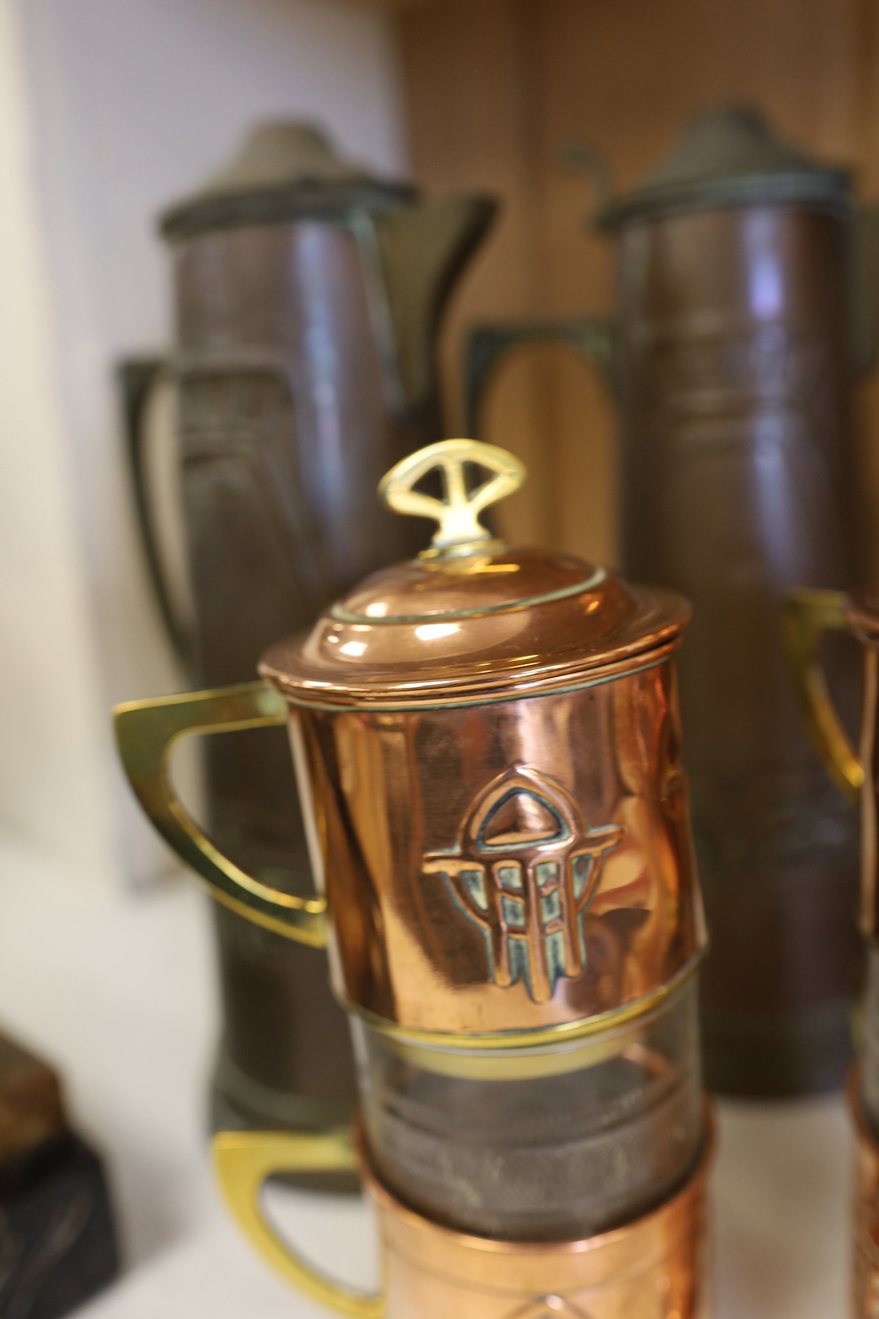 Three Art Nouveau mixed copper and brass coffee pots and two individual copper filter coffee glasses, tallest 36cm high (5). Condition - two pots need cleaning, but good condition for age